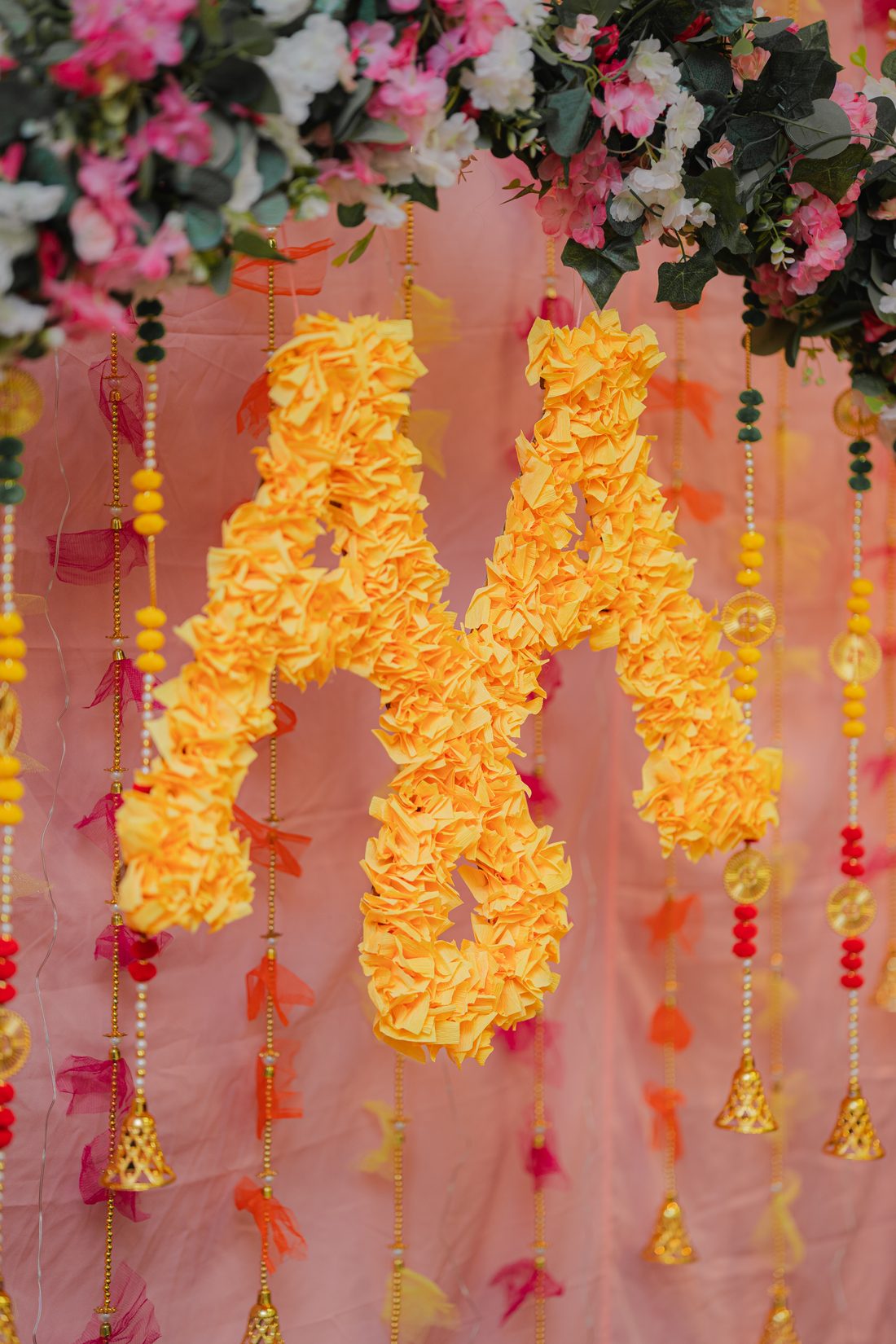 A marigold floral monogram on a haldi backdrop